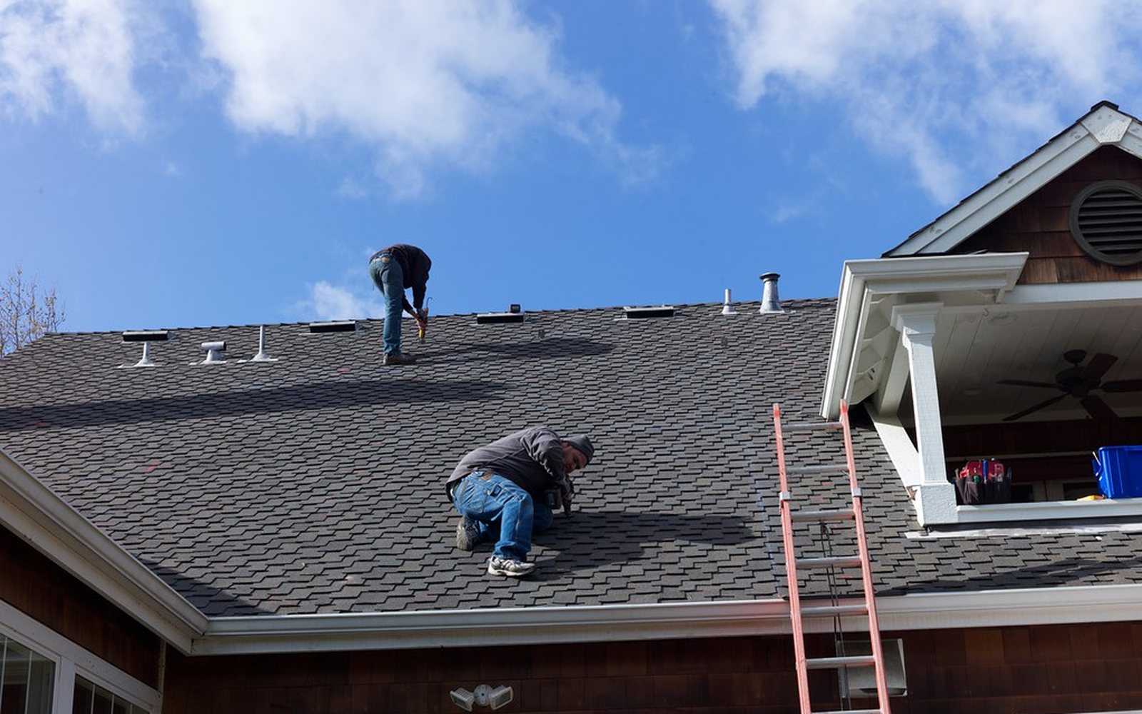 Roofing crew installing asphalt shingles on a residential roof